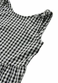 Abito a quadretti bianco e nero con spalline larghe, scollatura rotonda e vita arricciata. Il tessuto è leggero e a scacchi.
