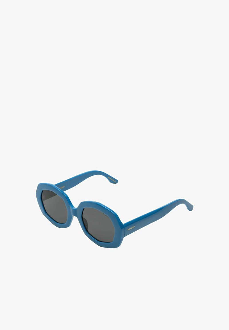 Lunettes de soleil bleues en forme d'octogone avec des verres sombres. La monture en plastique présente une texture lisse et des branches élégantes avec un détail de marque doré.