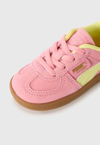 Roze zamjenska Puma tenisica s gumiranim potplatom, svijetložutom unutrašnjošću i Puma Formstrip detaljem na bijeloj pozadini.