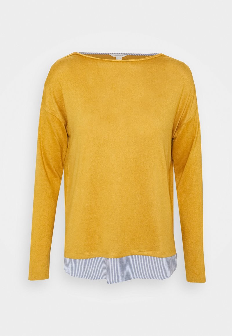 Pull à manches longues jaune moutarde superposé sur un bas de chemise rayée bleu et blanc sur fond uni.