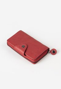 Red leather wallet with a snap closure and zipper around the edge. Features a smooth texture and a circular metal accent on the zipper pull.
