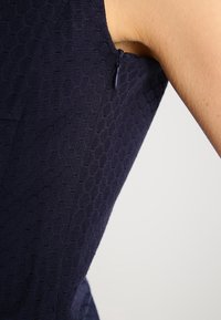 Navy Kleidungsstoff mit hexagonalem Muster, featuring einen verdeckten seitlichen Reißverschluss und eine taillierte Passform.