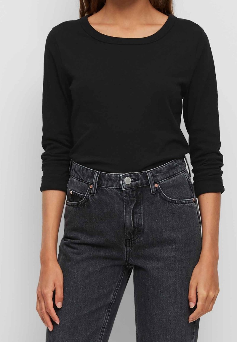 Zwarte lange mouwen top van katoen, met een ronde halslijn en aansluitende mouwen, gecombineerd met hoge zwarte denim jeans.