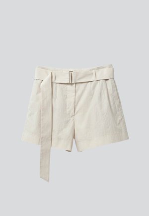 Magas derekú bézs lenvászon rövidnadrág, amelyhez illő szövetöv és szabott elülső gyűrődések tartoznak, egyszínű világosszürke háttéren bemutatva.