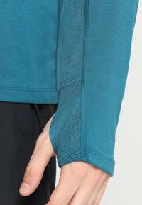Langarmshirt van teal stof, met een mesh accent nabij de pols, in een slim-fit ontwerp en een subtiel gemêleerd patroon.