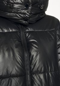 Černá péřová bunda s lesklou texturou, vybavená vysokým límcem, předním zipem a dekorativními knoflíkovými detaily.