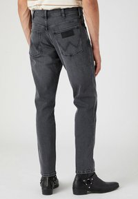 Szare dżinsy o slim fit, z pięcioma kieszeniami i czarną metką na tylnej kieszeni. Teksturowana tkanina z subtelnym wyblaknięciem.