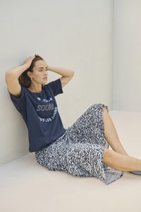 Tricou bleumarin cu text alb, asortat cu o fustă midi cu un model în bleumarin și alb. Croială lejeră, material moale, cu mâneci scurte și slituri laterale.