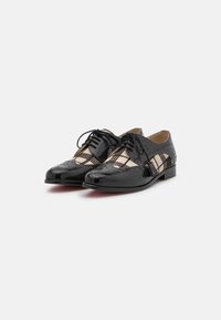 Scarpe in pelle nera con finitura lucida, dotate di dettagli perforati, design con lacci e un accento in tessuto a quadri sui lati.