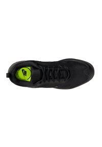 Zapato deportivo negro con parte superior de malla texturizada, puntera redonda y plantilla en contraste verde. Presenta un diseño de cordones y un cuello acolchado.
