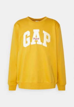 Sweat-shirt jaune avec col rond, manches longues et poignets côtelés. Présente un grand logo "GAP" blanc avec "Original" en rouge en dessous. Le matériau a une texture lisse.