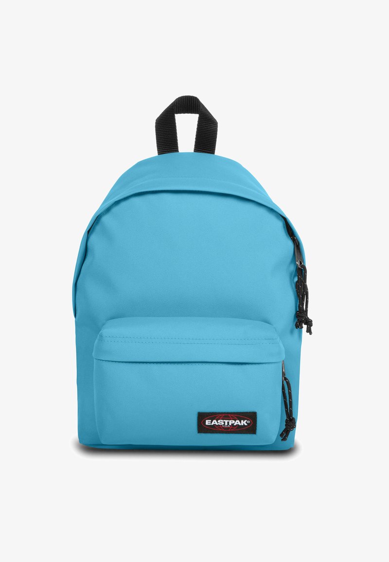 Mochila de tela azul con un compartimento principal, bolsillo frontal con cremallera y asa de transporte negra. Presenta tiradores de cremallera negros y etiqueta de marca.