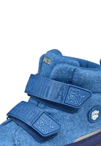 Scarpe in feltro blu con due cinturini in velcro testurizzati e dettagli in gomma, decorate con un motivo di elefante e un logo circolare.