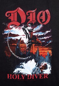 Camiseta negra con un diseño gráfico que presenta un fondo teñido de rojo, una figura encadenada y un texto en negrita que dice "DIO HOLY DIVER".