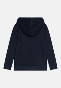 Sudadera azul marino con una capucha amplia, mangas largas y puños acanalados. El tejido parece suave y texturizado, diseñado para el uso casual.