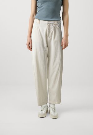 Pantalons blancs légers et amples avec une taille haute, dotés de deux poches latérales et d'une texture douce. Associés à des baskets blanches.