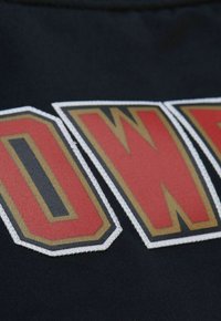 Schwarzer Stoff mit großen, gestickten Buchstaben "POWER" in Rot mit goldenen Akzenten, umrandet in Weiß. Glatte Textur mit auffälligem Design.