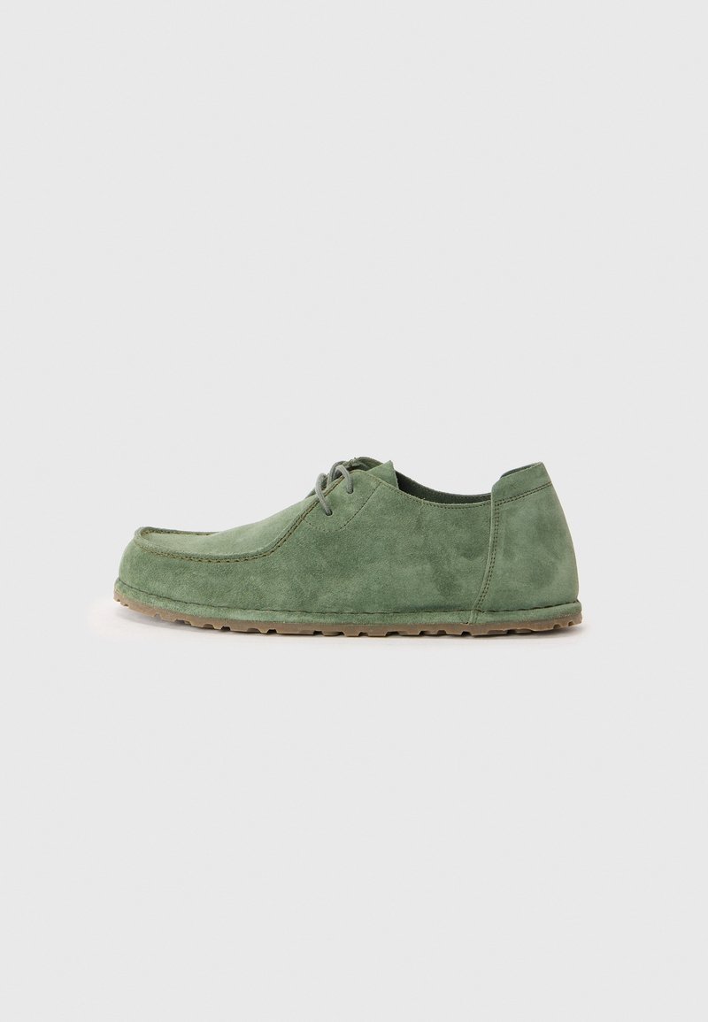 Chaussure décontractée pour homme en daim vert avec lacets à l’avant et semelle en caoutchouc texturée, présentée de profil sur fond neutre.