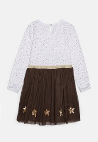 Vit långärmad topp med små guld- och grå stjärnor, fäst brun tyllkjol med guldpaljettstjärnor och glittrig guld midja.