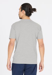 Harmaa lyhythihainen t-paita, joka on valmistettu puuvillasekoitteesta. Paidassa on pyöreä kaula-aukko ja rento istuvuus. Olkapäillä ja selässä näkyvät saumat.