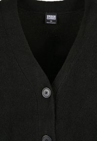 Black knitted cardigan featuring a v-neck design, textured fabric, and three large black buttons at the front. Label reads "URBAN CLASSICS, XS."