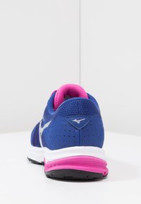 Baskets de sport bleu avec une tige en mesh et des accents roses, dotées d'une semelle rembourrée, d'une semelle intermédiaire blanche contrastante et de détails perforés.