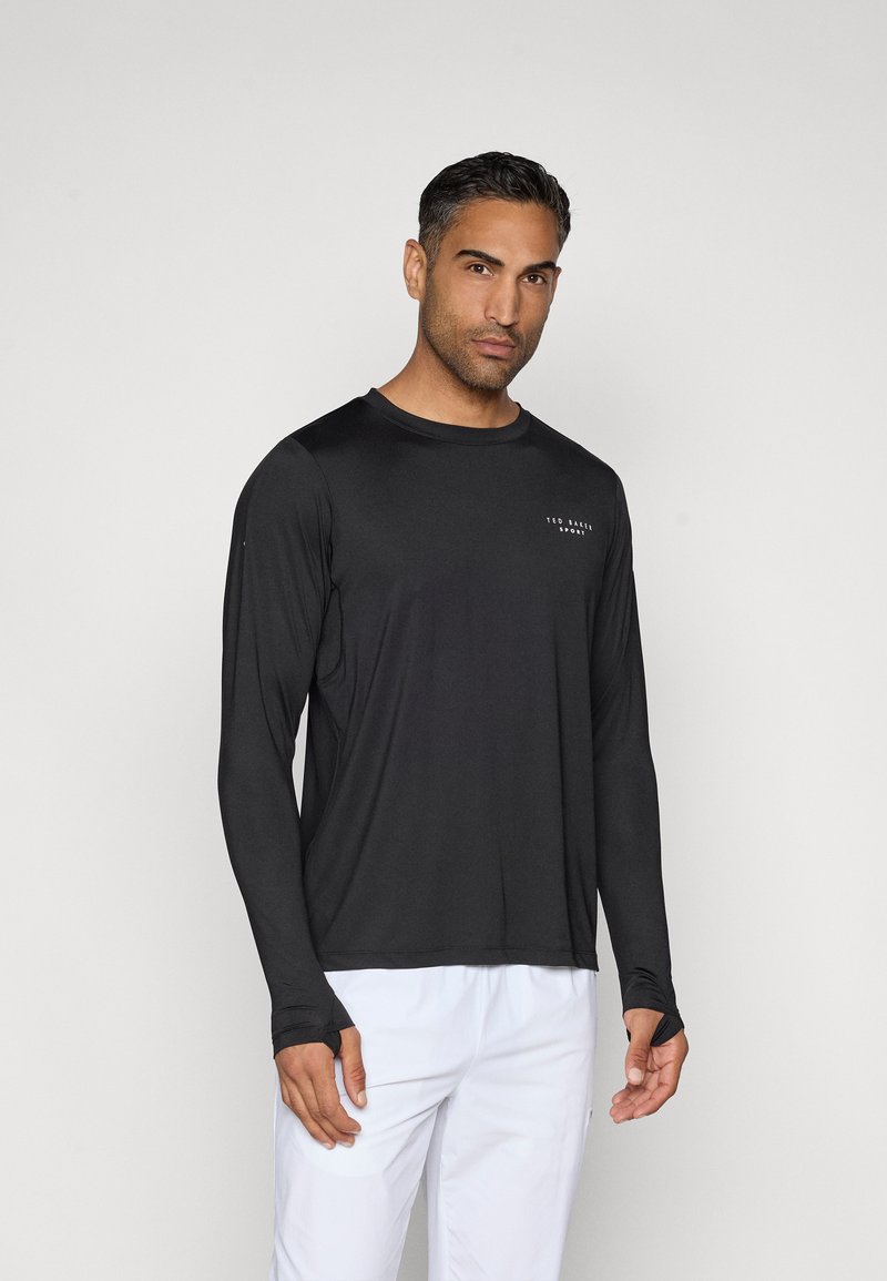 Tricou athletic cu mânecă lungă, de culoare neagră, realizat dintr-un material neted. Are un guler rotund și detalii cu logo pe piept; design ușor și ajustat.