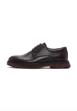 Chaussure habillée en cuir marron avec bout arrondi, design à lacets et semelle en liège texturée. Fini élégant et lisse avec des détails de couture subtils.