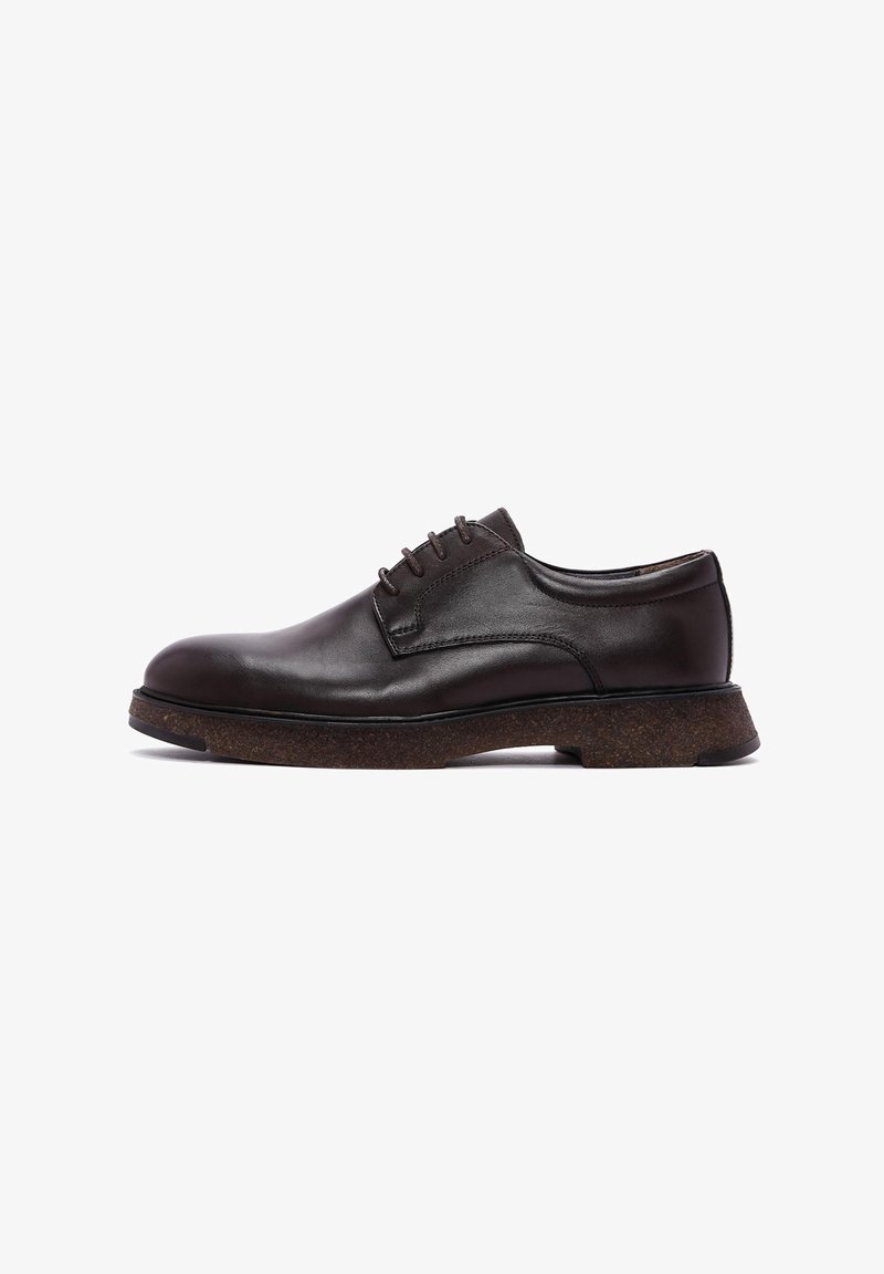 Chaussure habillée en cuir marron avec bout arrondi, design à lacets et semelle en liège texturée. Fini élégant et lisse avec des détails de couture subtils.