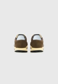 Brown suede sneakers with a yellow midsole, black outsole, and light blue heel embossed with "VEJA" logo. Rear view shows padding detail.