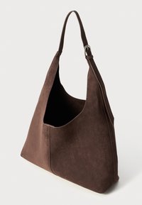 Sac à épaule en daim marron avec une grande ouverture, texture lisse et design minimaliste. Comprend une seule bandoulière réglable et des détails de couture.
