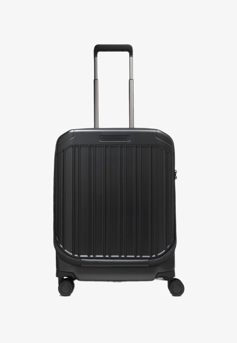 Valigia nera rigida con texture a costine verticali, due ruote lisce e manico retrattile sulla parte superiore.