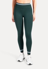 Athletiska leggings med hög midja i mörkgrönt med en texturerad yta och kontrasterande vita ränder vid midjan. Figursydd design för stöd.