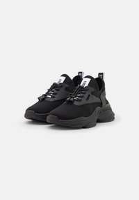 Schwarze Sportschuhe aus Mesh und Gummi. Mit einer strukturierten Sohle, Schnürsenkeln und einer Zuglasche an der Ferse. Minimalistisches Design.