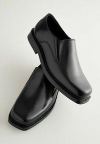 Musta nahkainen slip-on-kengät, joissa on neliönmuotoinen kärki, sileä pinta ja elastiset sivupaneelit. Varustettu matalalla pinottu kantapäällä ja ommelkoristeilla.