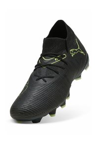 Botín de fútbol negro con superficie texturizada, acentos amarillos y un collar de punto. Presenta cordones y tacos de tracción para un mejor agarre.