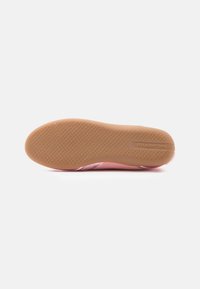 Πέλμα ροζ αθλητικού παπουτσιού με υφή καουτσούκ, που διαθέτει ανοιχτό καφέ ενδιάμεση σόλα και εγχάραξη επωνυμίας για κράτημα και σταθερότητα.