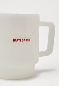 Frosted valkoinen savimuki, jossa on nelikulmainen kahva ja punainen teksti "HARTT OF SOUL" sivussa. Sileä pinta matta viimeistelyllä.