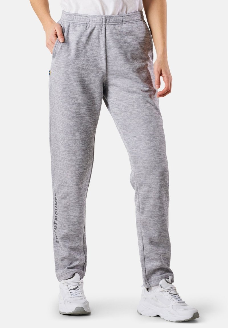 Harmaat collegehousut, jotka on valmistettu teksturoidusta kankaasta. Ne on varustettu elastisella vyötäröllä, sivutaskuilla ja brändäyksellä alaosassa. Yhdistettyten lenkkareihin.