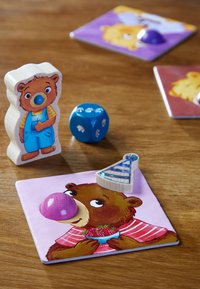 Drewniana figurka niedźwiedzia z malowanymi detalami, niebieskie kostki i kolorowe karty z ilustracjami niedźwiedzi. Teksturowane i żywe wzory.