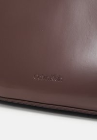 Calvin Klein REFINED SCULPT BAG SHINY - Bolso de mano - cioccolate lab