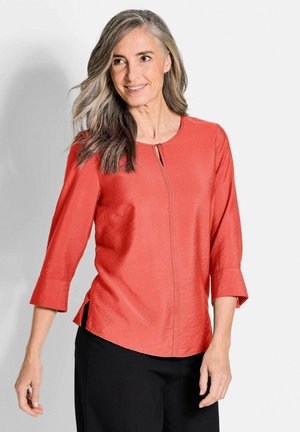 Rode blouse met driekwart mouwen, gemaakt van een soepele stof, met een ronde halslijn en een sleutelgatsluiting aan de voorkant; ontspannen pasvorm met zijsplitten.