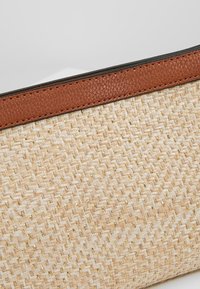 Borsa intrecciata in paglia con corpo beige testurizzato, dettagli dorati e rifinitura superiore in pelle marrone. Forma compatta e rettangolare.