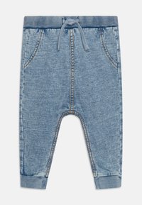 Pantalons jogger en denim bleu clair avec une taille élastique, un cordon de serrage, des poches latérales et des poignets côtelés. Comprend des détails de surpiqûres sur l'ensemble.