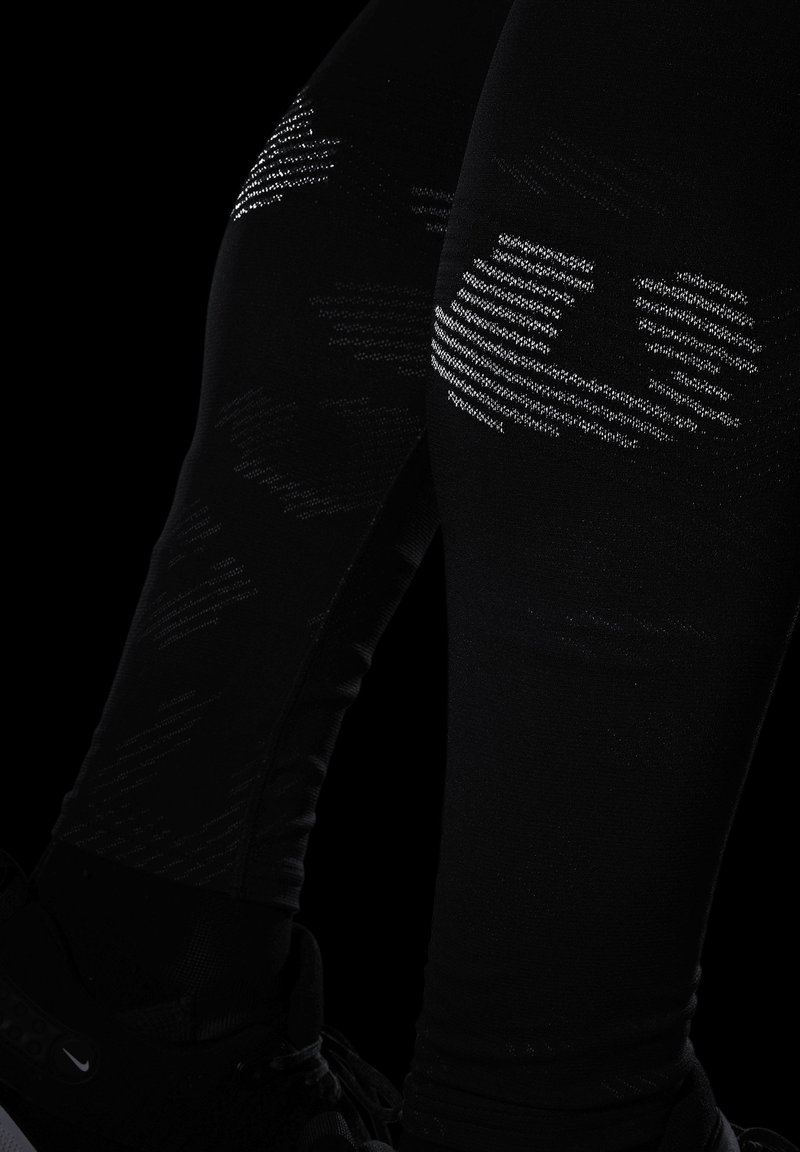 Leggings de sport noirs avec un motif texturé dans des nuances de gris. Le tissu est ajusté, avec une texture lisse et extensible.