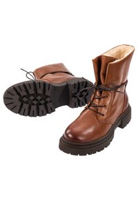 Botas de cuero marrón con forro de borrego, diseño de cordones, punta redondeada y suela de goma gruesa con un patrón de relieve resistente.