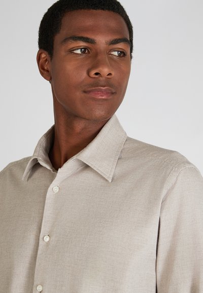 Lichtbrouw button-up shirt met een gladde textuur, klassieke kraag en zichtbare knopen. Eenvoudig ontwerp zonder patronen of accenten.