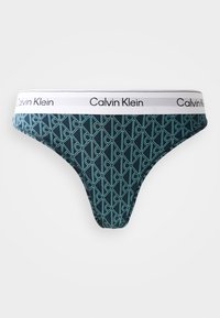 Mörkblå tanga med turkos geometrisk mönstring, med en vit midja som har "Calvin Klein"-logotypen. Gjord av mjukt, elastiskt tyg.