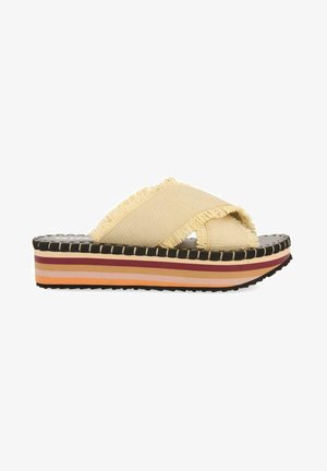 Platform sandals with beige fabric straps featuring frayed edges. Multicolored striped sole in shades of pink, orange, and burgundy.