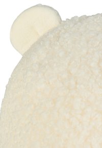 Cream-colored plush hat featuring textured fabric with rounded ear accents, designed with a soft, fluffy appearance and a smooth crown.
